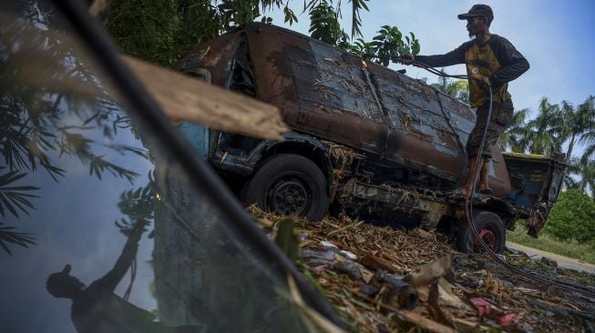 Seorang pekerja memotong bangkai angkot menggunakan las di Depok, Jawa Barat, Minggu (5/9/2021). [ANTARA FOTO/Wahyu Putro A]