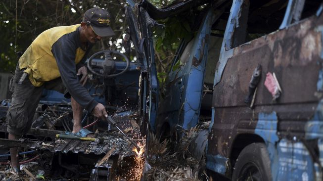 Seorang pekerja memotong bangkai angkot menggunakan las di Depok, Jawa Barat, Minggu (5/9/2021). [ANTARA FOTO/Wahyu Putro A]