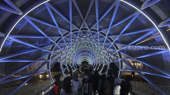 Warga berada di Jembatan Penyeberangan Orang (JPO) Lenteng Agung, Jakarta, Minggu (5/9/2021) malam. [Suara.com/Angga Budhiyanto]