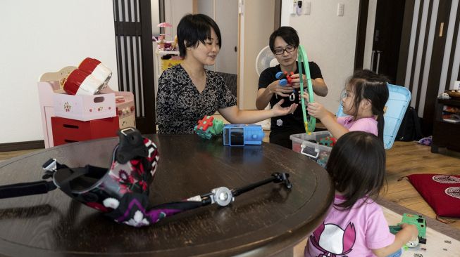 Pemain biola Jepang Manami Ito (kiri) berinteraksi dengan putrinya Miu dan Mei dan suaminya Yuki (kedua kiri) di kediaman mereka di Shizuoka, Jepang, pada (28/8/2021). [Yuki IWAMURA / AFP]