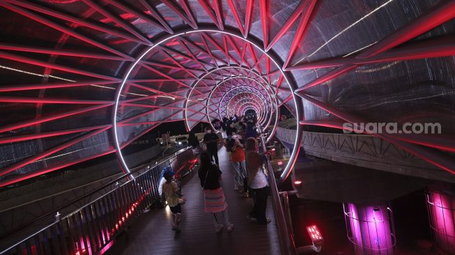 Warga berada di Jembatan Penyeberangan Orang (JPO) Lenteng Agung, Jakarta, Minggu (5/9/2021) malam. [Suara.com/Angga Budhiyanto]