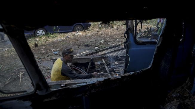 Seorang pekerja memotong bangkai angkot menggunakan las di Depok, Jawa Barat, Minggu (5/9/2021). [ANTARA FOTO/Wahyu Putro A]