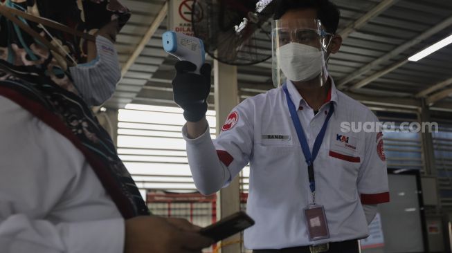 Petugas memeriksa suhu tubuh calon penumpang yang akan melakukan perjalanan menggunakan KAI Commuter Line di Stasiun Manggarai, Jakarta, Senin (6/9/2021). [Suara.com/Angga Budhiyanto]