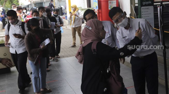 Calon penumpang memindai kode batang dari aplikasi PeduliLindungi sebelum melakukan perjalanan menggunakan KAI Commuter Line di Stasiun Manggarai, Jakarta, Senin (6/9/2021). [Suara.com/Angga Budhiyanto]