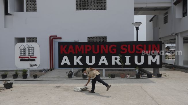 Warga berada di depan papan nama Kampung Susun Akuarium, Penjaringan, Jakarta, Senin (6/9/2021). [Suara.com/Angga Budhiyanto]