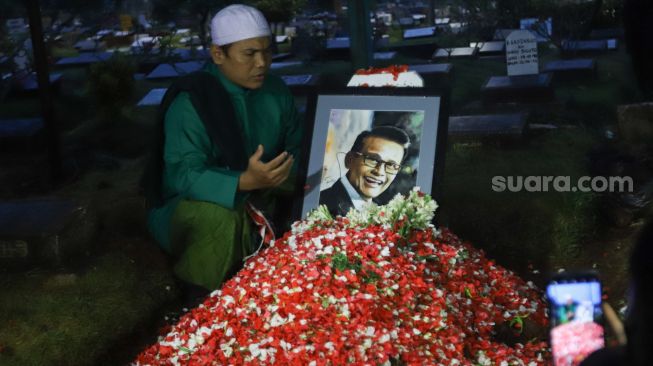 Keluarga berdoa diatas pusara Penyanyi Koes Hendratmo usai dimakamkan di TPU Karet Bivak, Jakarta Pusat, Selasa (7/9/2021). [Suara.com/Alfian Winanto]