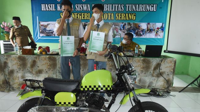 Dua siswa tuna rungu SKH Negeri 02 Serang Sodikin (kiri) dan Edo (kanan) memegang sertifikat penghargaan saat peluncuran sepeda motor rancangannya di Serang, Banten, Selasa (7/9/2021). ANTARA FOTO/Asep Fathulrahman