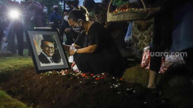 Keluarga berdoa diatas pusara Penyanyi Koes Hendratmo usai dimakamkan di TPU Karet Bivak, Jakarta Pusat, Selasa (7/9/2021). [Suara.com/Alfian Winanto]