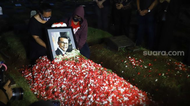 Keluarga berdoa diatas pusara Penyanyi Koes Hendratmo usai dimakamkan di TPU Karet Bivak, Jakarta Pusat, Selasa (7/9/2021). [Suara.com/Alfian Winanto]