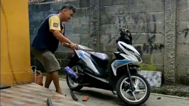 Seorang pria menyiksa sebuah motor Honda BeAT menggunakan pedang samurai (TikTok)