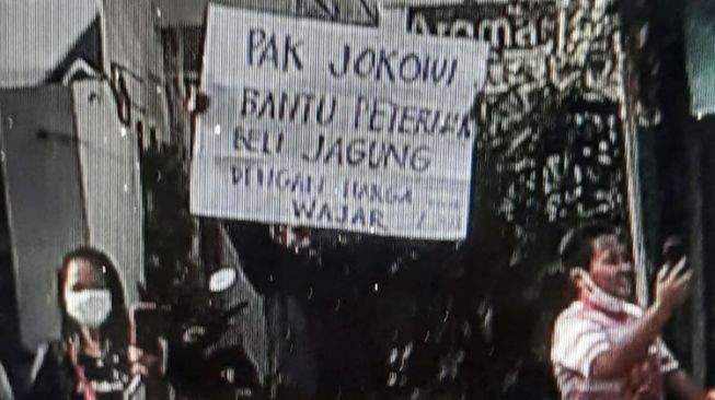 Tangkapan layar video seorang pria membentangkan poster saat kunjungan Presiden Jokowi ke Kota Blitar, Selasa (7/9/2021). [Foto: Times Indonesia/Istimewa]