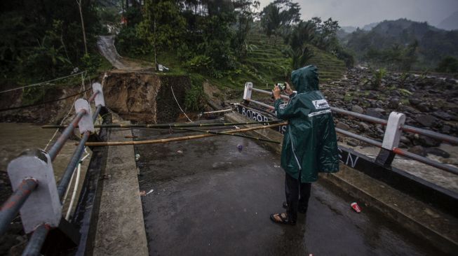 Warga melihat kondisi jembatan perbatasan Kecamatan Sukajaya dan Kecamatan Nanggung yang terputus di Desa Urug, Sukajaya, Kabupaten Bogor, Jawa Barat, Selasa (7/9/2021). ANTARA FOTO/Yulius Satria Wijaya