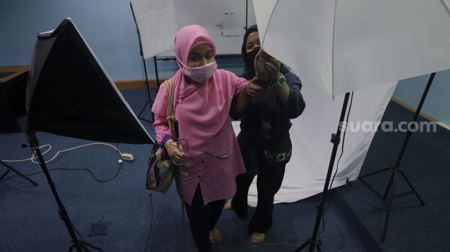 Relawan mendampingi mahasiswa penyandang disabilitas tunanetra saat orientasi mobilitas fakultas di kampus Universitas Muhammadiyah Jakarta (UMJ), Ciputat, Tangerang Selatan, Banten, Kamis (9/9/2021). [Suara.com/Angga Budhiyanto]