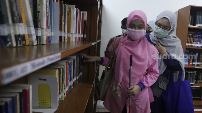 Relawan mendampingi mahasiswa penyandang disabilitas tunanetra saat orientasi mobilitas fakultas di kampus Universitas Muhammadiyah Jakarta (UMJ), Ciputat, Tangerang Selatan, Banten, Kamis (9/9/2021). [Suara.com/Angga Budhiyanto]