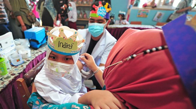 Seorang murid kelas 1 SD mendapatkan suntikan vaksin campak dari tenaga kesehatan di ruang kelas yang dihiasi ornamen pesta ulang tahun di SDN 28 Kota Jambi, Jambi, Kamis (9/9/2021).  ANTARA FOTO/Wahdi Septiawan
