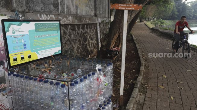 Pesepeda melintas di dekat tempat sampah dari botol bekas yang berada di kawasan Situ Gintung, Tangerang Selatan, Banten, Kamis (9/9/2021). [Suara.com/Angga Budhiyanto]