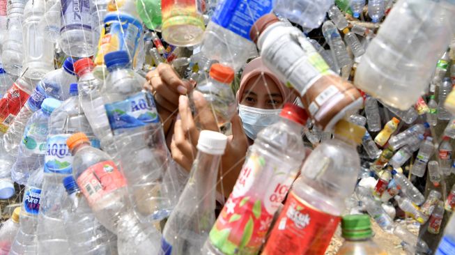 Relawan mengaitkan botol plastik bekas saat pembuatan instalasi Museum Plastik di Ecological Observation and Wetlands Conservation (Ecoton) di Gresik, Jawa Timur, Kamis (9/9/2021).  ANTARA FOTO/Zabur Karuru