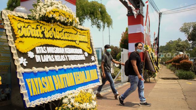 Warga melintas di depan karangan bunga di Lapas Kelas 1 Tangerang, Banten, Jumat (10/9). [Suara.com/ Hilal Rauda Fiqry]