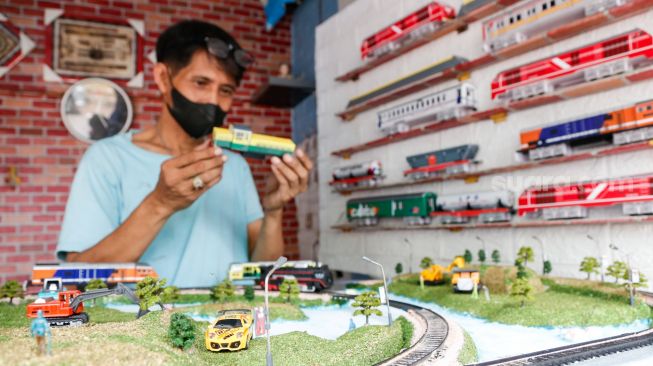 Iskandar (53) mengecek ulang hasil miniatur kereta api yang dibuatnya di kiosnya kawasan Manggarai, Jakarta Selatan, Sabtu (11/9/2021). [Suara.com/Alfian Winanto]