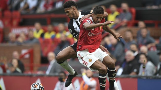 Striker Newcastle United Joelinton (kiri) bersaing dengan bek Manchester United Raphael Varane selama pertandingan sepak bola Liga Premier Inggris antara Manchester United dan Newcastle di Old Trafford, Manchester, Inggris, Sabtu (11/9/2021). [Oli SCARFF / AFP]