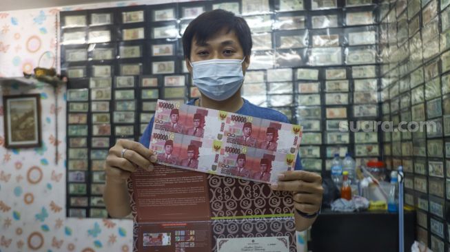 David, pedagang mata uang kuno menunjukkan uang pecahan Rp.100.000,- edisi terbatas di Pasar Baru, Jakarta Pusat, Sabtu (11/9/2021). [Suara.com/Alfian Winanto]