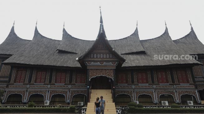 Pengunjung berfoto di anjungan Provinsi Sumatera Barat di Taman Mini Indonesia Indah (TMII), Jakarta, Minggu (12/9/2021). [Suara.com/Angga Budhiyanto]