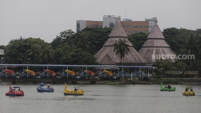 Pengunjung menaiki wahana perahu bebek di Taman Mini Indonesia Indah (TMII), Jakarta, Minggu (12/9/2021). [Suara.com/Angga Budhiyanto]