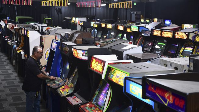 Karyawan rumah lelang bermain video game saat menguji mesin yang akan dilelang di Museum of Pinball di Banning, California, pada (10/9/2021). [Frederic J. BROWN / AFP]