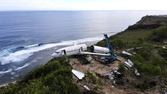 Foto udara aktivitas pengerjaan perakitan badan pesawat bekas di kawasan Pantai Nyang-Nyang, Badung, Bali, Minggu (12/9/2021). [ANTARA FOTO/Fikri Yusuf]