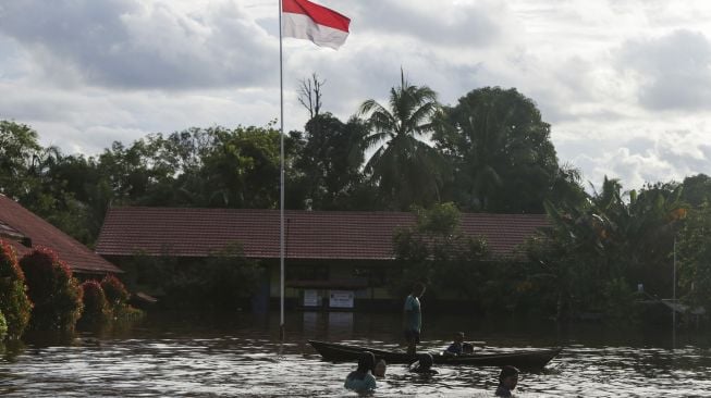 Anak-anak bermain di halaman sekolah dasar yang terendam banjir di Desa Petak Bahandang, Kabupaten Katingan, Kalimantan Tengah, Sabtu (11/9/2021). [ANTARA FOTO/Makna Zaezar]