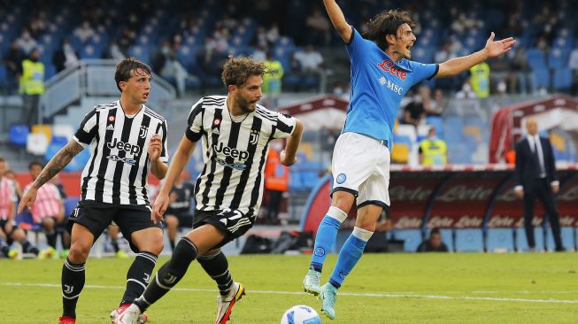 Gelandang Napoli Eljif Elmas (kanan) bereaksi di dekat gelandang Juventus Manuel Locatelli dan bek Juventus Luca Pellegrini (kiri) selama pertandingan sepak bola Serie A antara Napoli dan Juventus di Stadion Maradona, Naples, Italia, pada (11/9/2021). [Carlo Hermann / AFP]