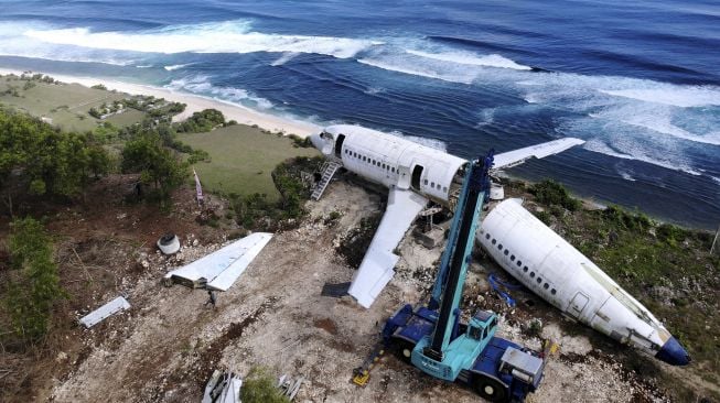 Foto udara aktivitas pengerjaan perakitan badan pesawat bekas di kawasan Pantai Nyang-Nyang, Badung, Bali, Minggu (12/9/2021). [ANTARA FOTO/Fikri Yusuf]