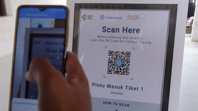 Wisatawan melakukan scan QR Code sertifikat vaksin COVID-19 melalui aplikasi PeduliLindungi saat hari pertama uji coba pembukaan Daya Tarik Wisata (DTW) Uluwatu, Badung, Bali, Senin (13/9/2021). [ANTARA FOTO/Nyoman Hendra Wibowo]