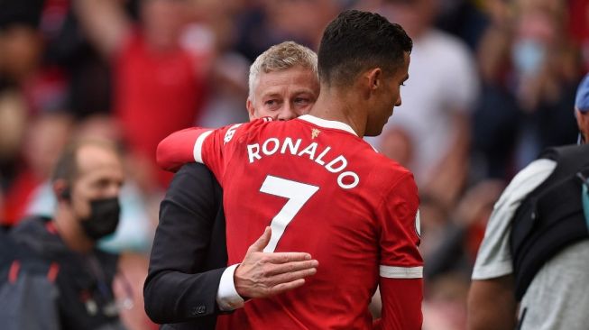 Megabintang Manchester United, Cristiano Ronaldo (kanan) berpelukan dengan sang pelatih, Ole Gunnar Solskjaer seusai laga Liga Inggris kontra Newcastle United di Old Trafford, Manchester, Sabtu (11/9/2021) malam WIB. [OLI SCARFF / AFP]