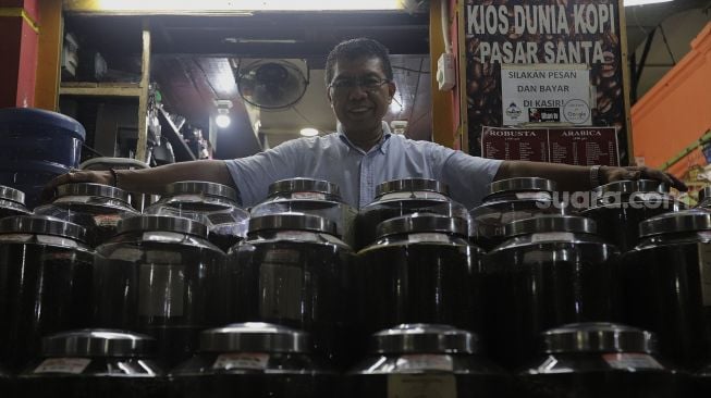 Pemilik Dunia Kopi, Suradi (42) berpose di kiosnya di Pasar Santa, Jakarta, Selasa (14/9/2021). [Suara.com/Angga Budhiyanto]