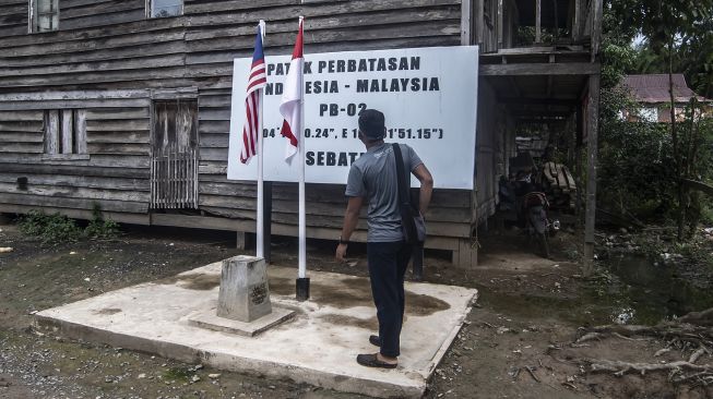 Wisatawan berdiri di atas patok perbatasan Indonesia-Malaysia di Pulau Sebatik, Senin (13/9/2021). ANTARA FOTO/Muhammad Adimaja