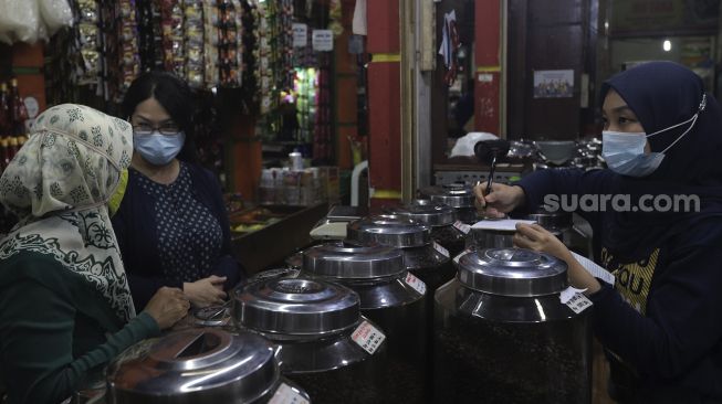 Pekerja melayani pembeli di kios Dunia Kopi, Pasar Santa, Jakarta, Selasa (14/9/2021). [Suara.com/Angga Budhiyanto]