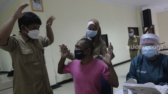 Petugas menghibur orang dengan gangguan jiwa (ODGJ) sebelum mendapatkan vaksinasi COVID-19 di Panti Sosial Bina Insan Bangun Daya 2, Cipayung, Jakarta, Selasa (14/9/2021). [Suara.com/Angga Budhiyanto]