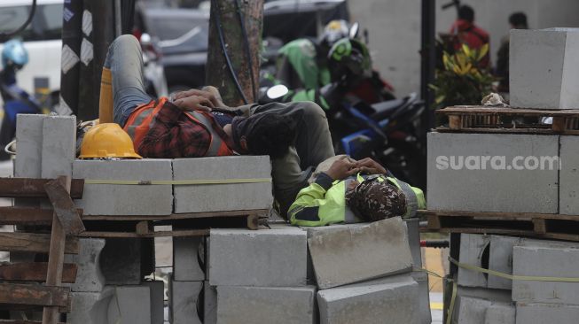 Pekerja beristirahat di sela menyelesaikan proyek revitalisasi trotoar di Jalan Wolter Monginsidi, Kebayoran Baru, Jakarta, Rabu (15/9/2021). [Suara.com/Angga Budhiyanto]