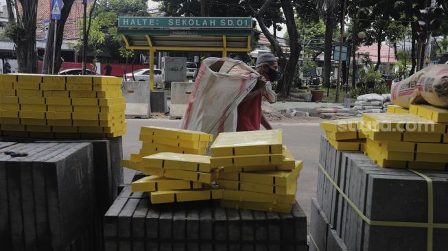 Warga berjalan di dekat proyek revitalisasi trotoar di Jalan Senopati, Kebayoran Baru, Jakarta, Rabu (15/9/2021). [Suara.com/Angga Budhiyanto]