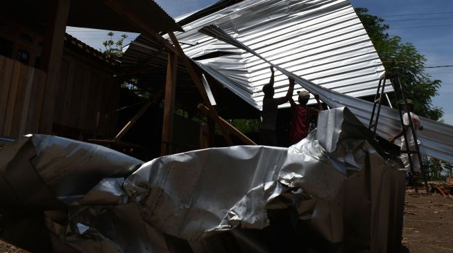 Warga memperbaiki rumah yang rusak akibat angin puting beliung di Desa Kedungrejo, Kecamatan Balerejo, Kabupaten Madiun, Jawa Timur, Rabu (15/9/2021). ANTARA FOTO/Siswowidodo
