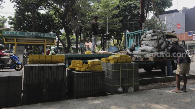 Pekerja menurunkan material proyek revitalisasi trotoar di Jalan Senopati, Kebayoran Baru, Jakarta, Rabu (15/9/2021). [Suara.com/Angga Budhiyanto]