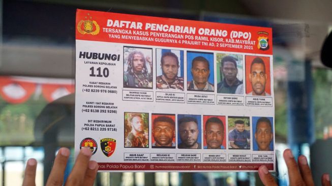 Polisi menempelkan stiker Daftar Pencarian Orang di Pintu keluar masuk Pelabuhan Laut Kota Sorong, Papua Barat, Kamis (16/9/2021).  ANTARA FOTO/Olha Mulalinda
