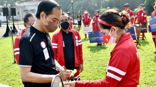 Momen Presiden Jokowi berbagi kenang-kenangan dengan atlet bulutangkis Paralimpiade Tokyo Leani Ratri Oktila. [Ist] 