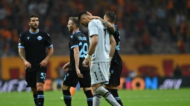 Potret kiper Lazio, Thomas Strakosha disemangati rekan setimnya usai lakukan gol bunuh diri konyol. (OZAN KOSE / AFP)