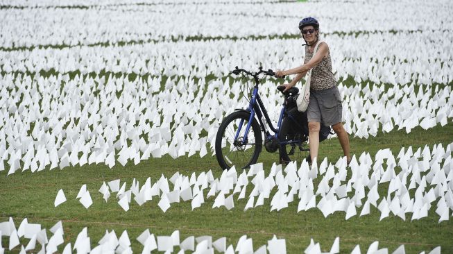 Warga mendorong sepedanya melewati bendera putih di dekat Monumen Washington, Washington, DC, pada (16/9/2021). [MANDEL NGAN / AFP]