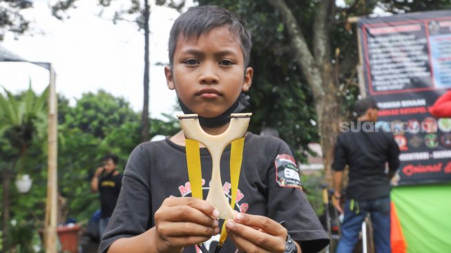 Seorang anak menunjukkan ketapel yang akan digunakannya untuk kompetisi di Kampung Ketapel, Ciganjur, Jakarta Selatan, Minggu (19/9/2021). [Suara.com/Alfian Winanto]