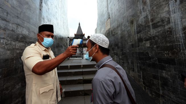 Petugas dinas pariwisata memeriksa suhu peziarah di gerbang masuk Kawasan Wisata Makam Presiden Soekarno di Kota Blitar, Jawa Timur, Selasa (21/9/2021).  ANTARA FOTO/Irfan Anshori