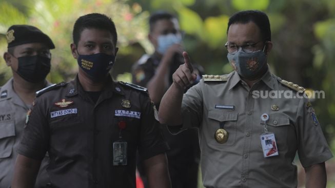 Gubernur DKI Jakarta Anies Baswedan (kanan) berjalan setibanya di Gedung Merah Putih KPK, Jakarta, Selasa (21/9/2021). [Suara.com/Angga Budhiyanto]