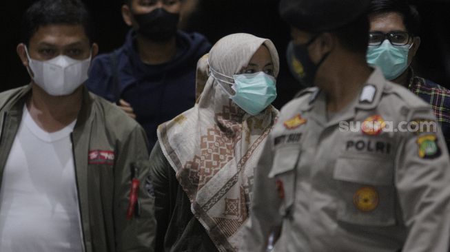 Bupati Kolaka Timur Andi Merya Nur (tengah) berjalan setibanya di Gedung Merah Putih KPK, Jakarta, Rabu (22/9/2021) malam. [Suara.com/Angga Budhiyanto]